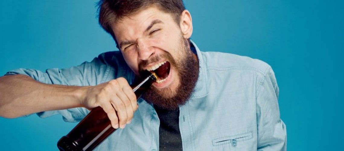 Man opening bottle with teeth