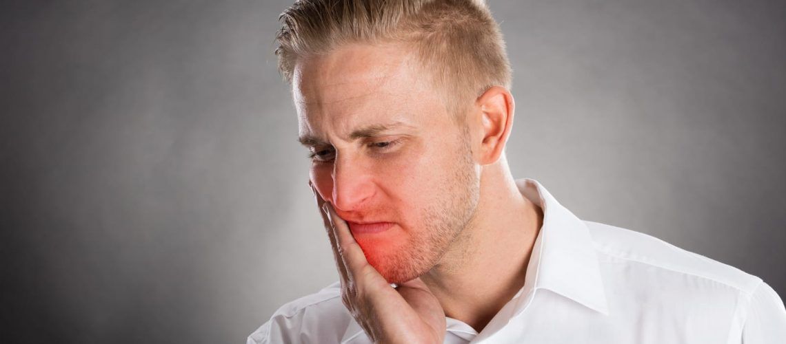 Man Holding Face In Pain